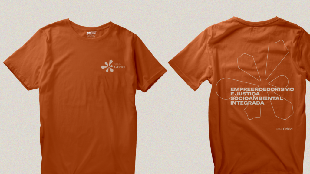 Mockup de Blusa laranja com a marca pequeno em frente ao peito esquerdo. Nas costas a marca em outline e a tagline "Empreendedorismo Diverso e Inclusivo"